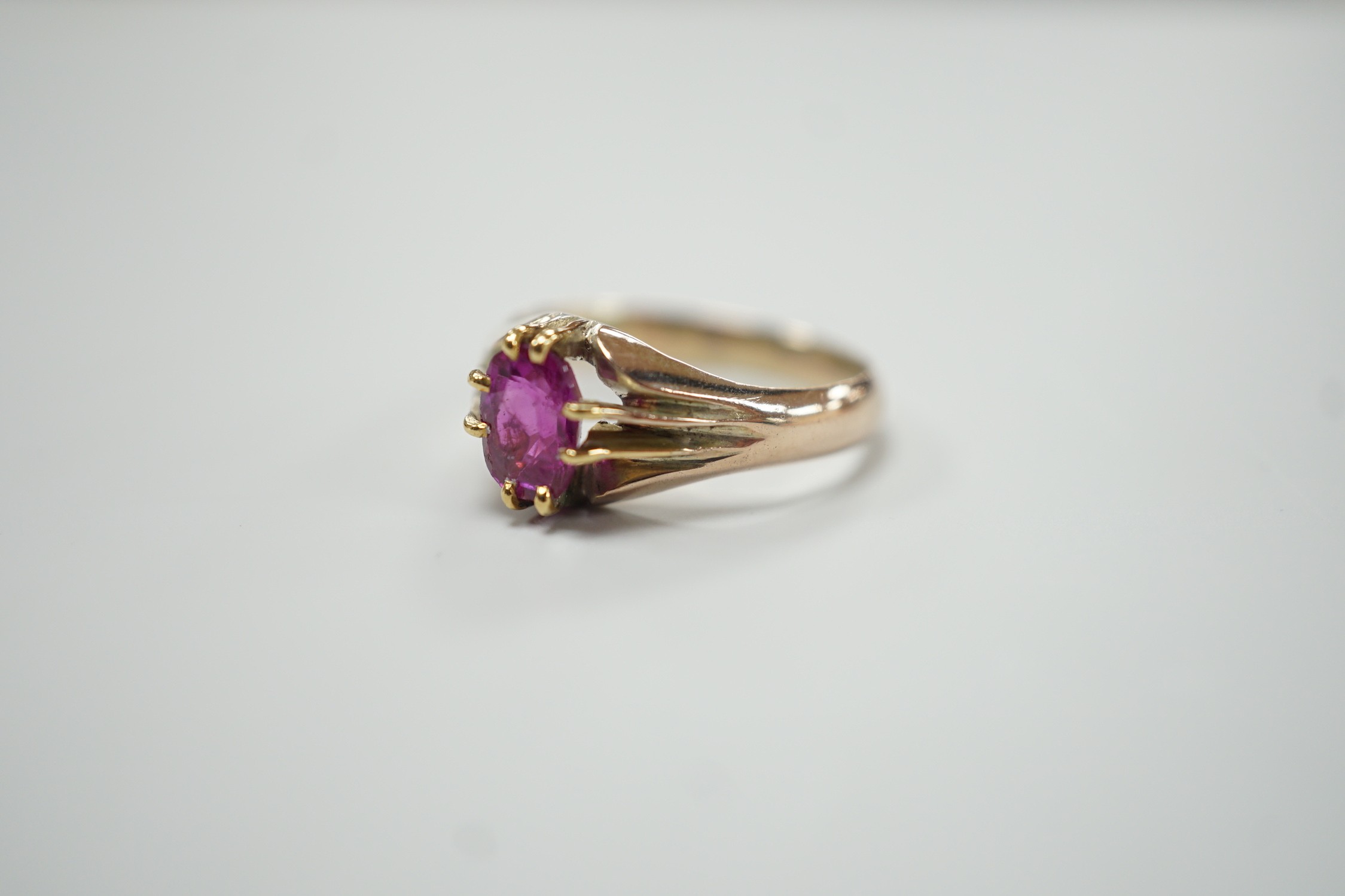 A yellow metal and claw set solitaire oval cut ruby/pink sapphire? ring, size L, gross weight 3.3 grams